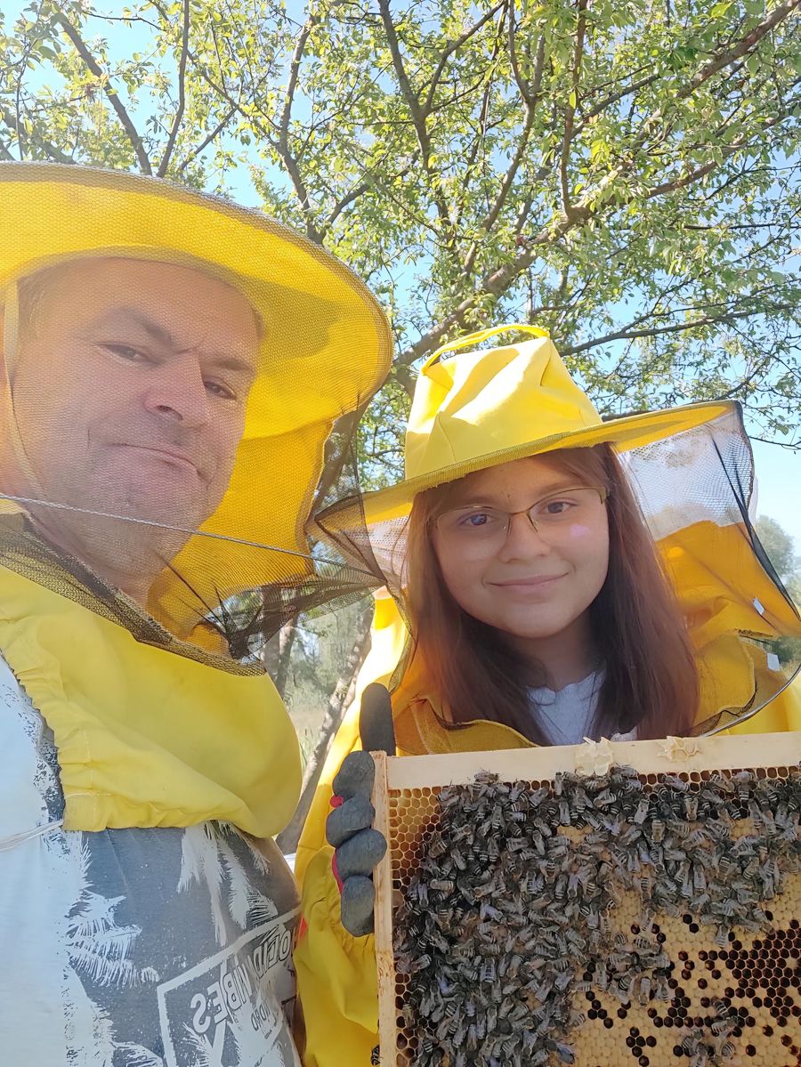 Pčelar i djevojčica u zaštitnim odijelima s okvirom pčela